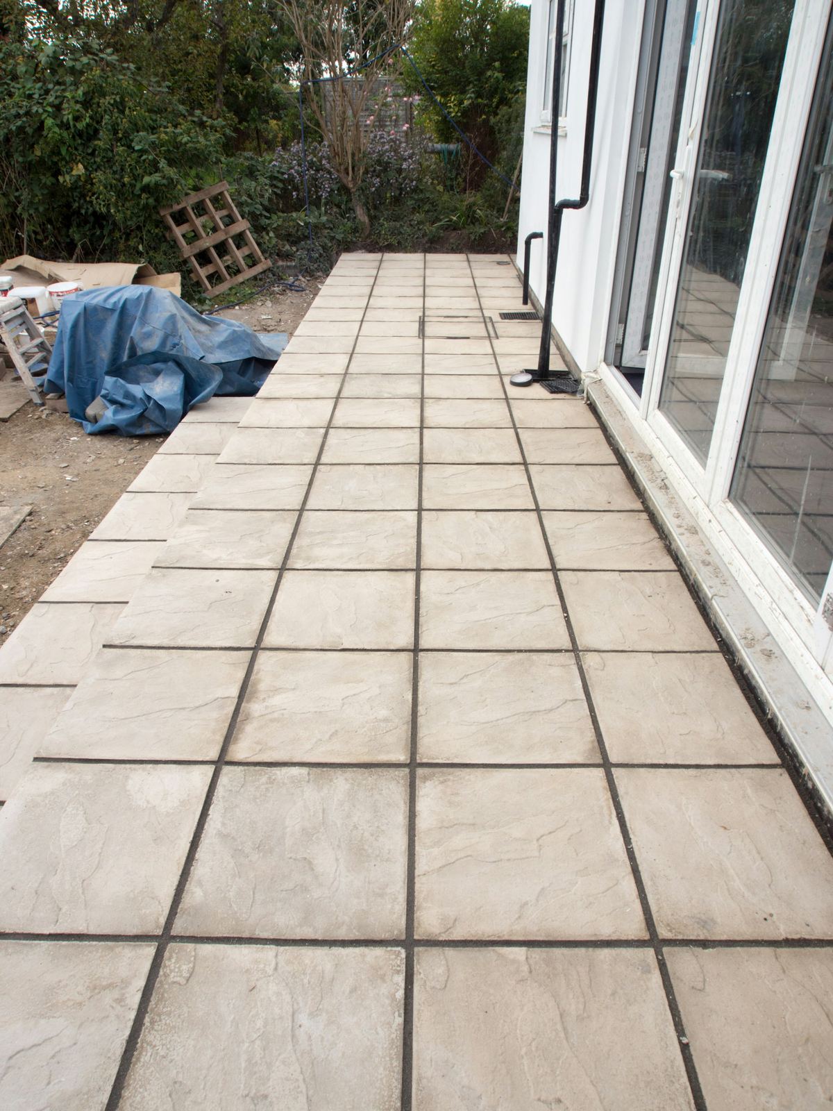 Newly installed large-format pavers along the back of a house